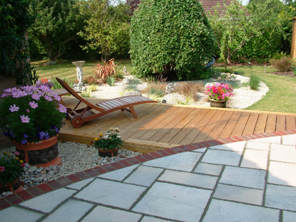 garden design restful seating area deck and mature Cotswold stone raised to view an island bed with grasses and scented plants